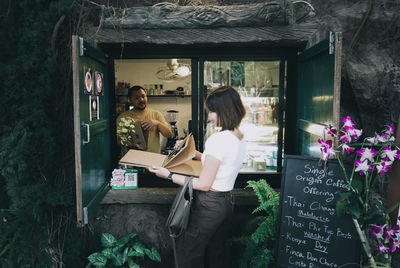 Man looking at woman reading menu while standing outside coffee shop