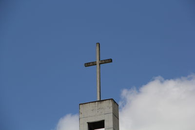 Low angle view of cross on building against sky