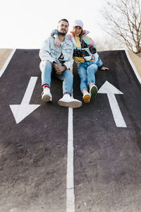 Young couple sitting between the signs on the floor of a skate park