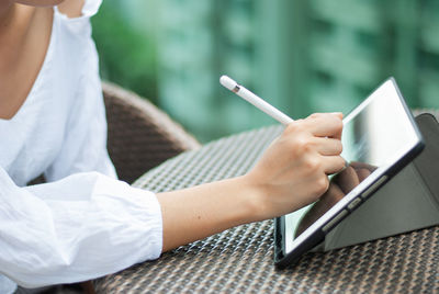 Midsection of woman using mobile phone while sitting outdoors