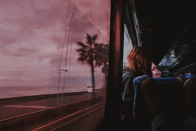Rear view of man looking through train window