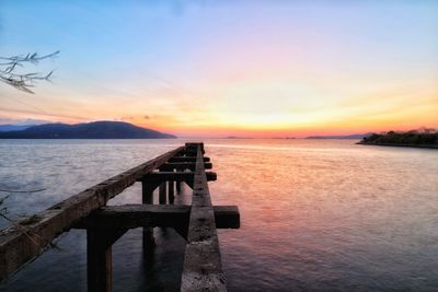 Pier over sea against sky during sunset