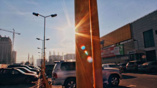 Cars on road by buildings in city at sunset