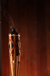 Close-up of tiki torch against wooden wall