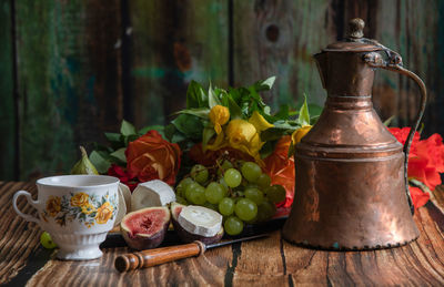 Cheese plate with goat cheese, grapes and figs, copper teapot, angle view