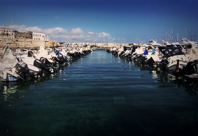 Motorboats moored at harbor against sky