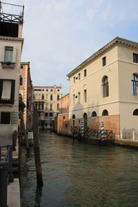 Canal amidst buildings against sky