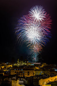 Firework display in  city against sky at night