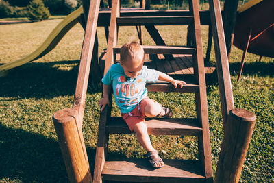 Full length of boy sitting on slide at playground