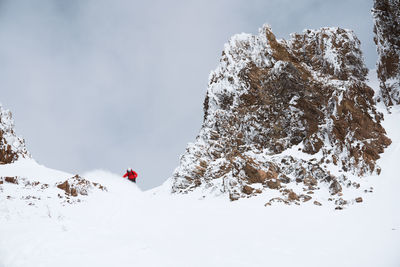 Snowboarder in red jacket making a turn in the mountains