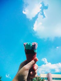 Midsection of person holding ice cream against sky