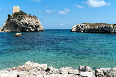 Scenic view of rocks in sea against blue sky