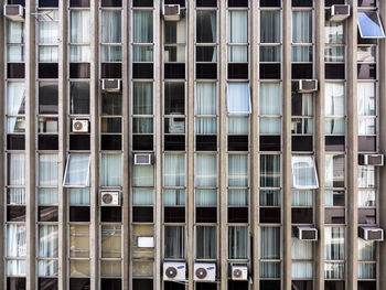 Commercial building facade with windows, blinds and air conditioners