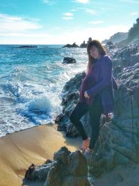 Young woman on beach against sky