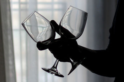 Cropped image of silhouette person holding wineglasses