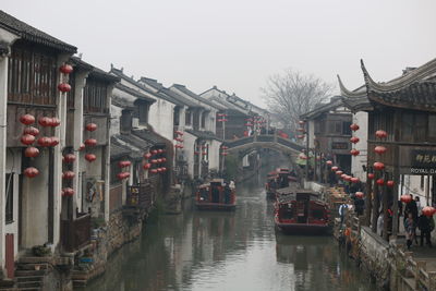 Canal amidst buildings in city against sky