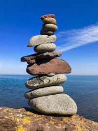 Stack of stones in sea against sky