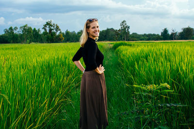 Portrait of woman standing on field against sky