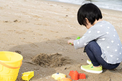 3 years old asian kid play sand on the beach. background for family life and education