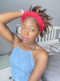 Portrait of smiling young woman wearing sunglasses while lying on bed at home