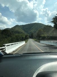 Road amidst trees against sky seen through car windshield