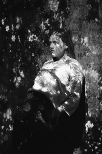 Woman standing by tree against plants