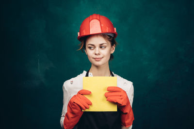 Portrait of smiling young woman standing against red wall