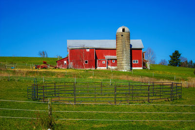 Agricultural field with red barn against clear blue sky