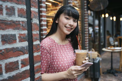 Portrait of smiling young woman holding ice cream outdoors