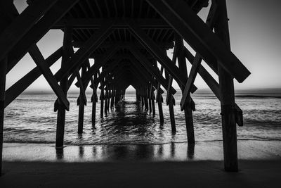 Silhouette of pier on beach against sky