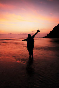 Silhouette man standing on beach against sky during sunset