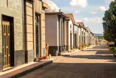 Street amidst buildings against sky on sunny day