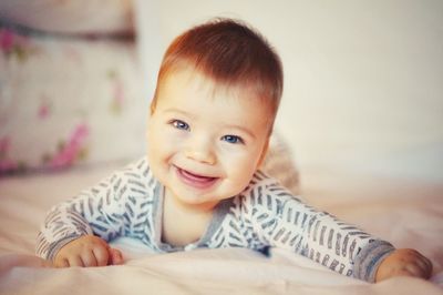 Portrait of cute baby girl lying on bed