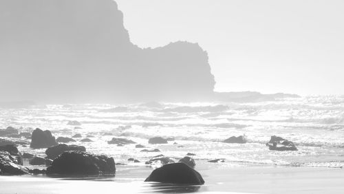 Silhouette rocks on shore against sky