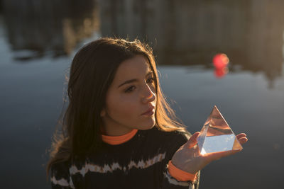 Young woman holding crystal by lake