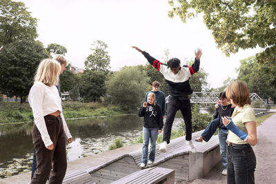 Group of teenagers walking on benches at river