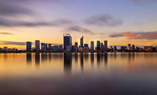 Sea by city against sky during sunset