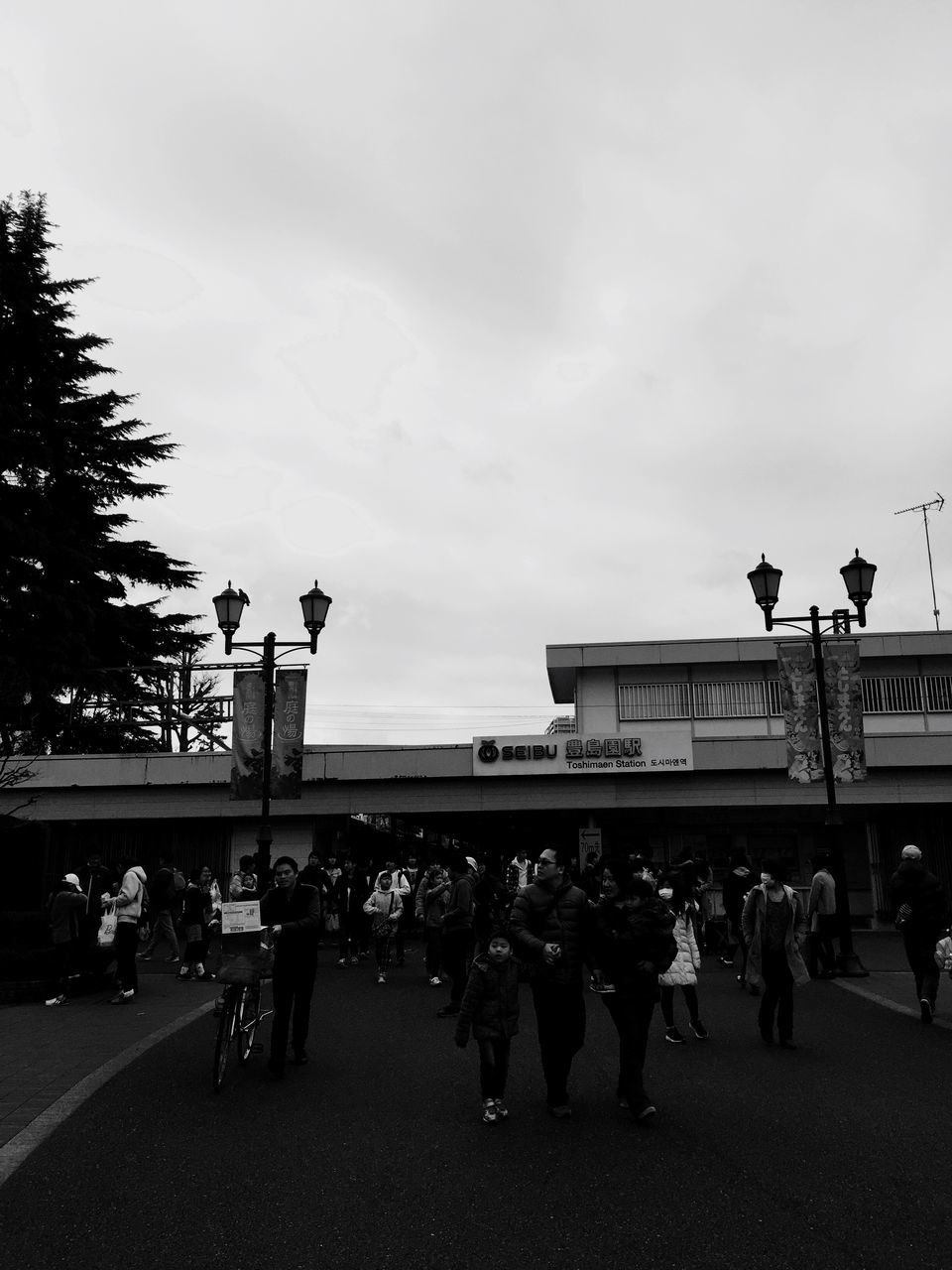 architecture, built structure, large group of people, men, sky, building exterior, street, person, transportation, city, road, walking, lifestyles, city life, leisure activity, street light, bird, city street, outdoors