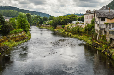 River amidst trees and buildings against sky