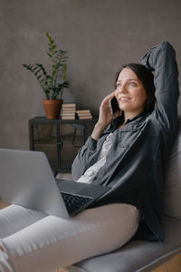 Young woman using mobile phone while sitting on sofa