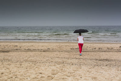 Rear view of woman with umbrella standing on field