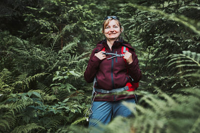 Woman with backpack hiking in forest, actively spending summer vacation close to nature