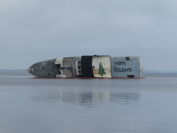 Reflection of text on sea against sky