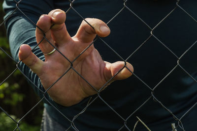 Male hand through a metal mesh