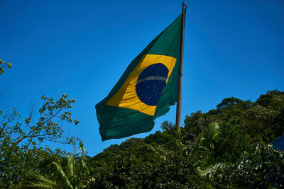 Low angle view of flag against clear blue sky