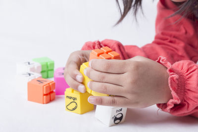 Close-up midsection of girl playing with toy blocks against white background