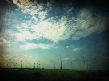 Windmill on field against cloudy sky