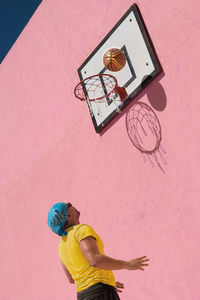 Low angle view of man playing basketball during sunny day