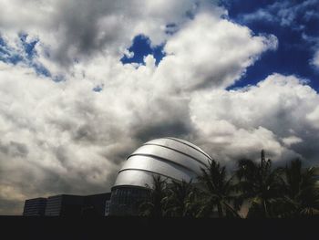 Low angle view of palm trees and building against sky