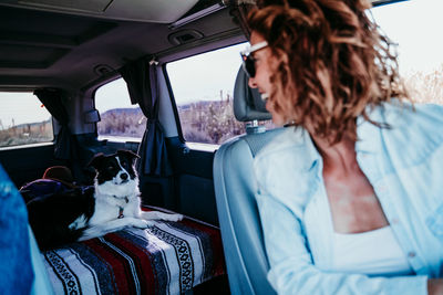 Woman looking at dog while sitting in camper trailer